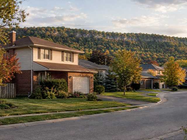 A two-storey family home on a curving Stoney Creek street with the wooded escarpment behind